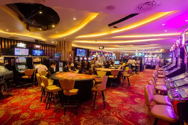 A young woman relaxing with her phone while dynamic casino elements float around her, illustrating the smooth mobile experience offered by the GGGJL app.