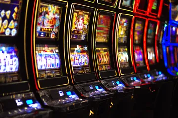 A woman smiling by bright slot machines showing lucky symbols, showcasing the exciting slot offerings at GGGJL.
